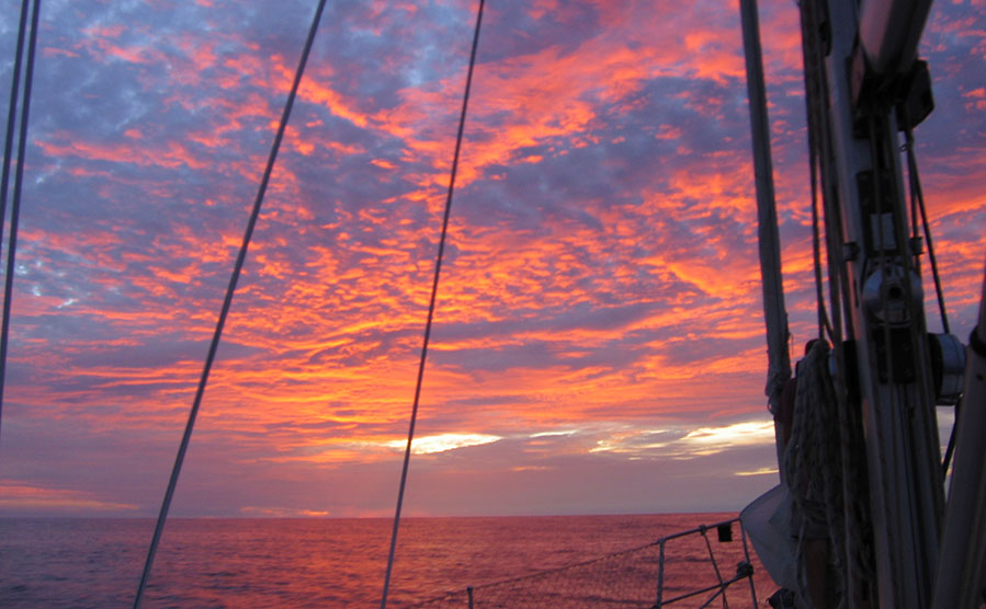 Sailors enjoying sunset at sea during the Atlantic crossing on a Challenger 72 yacht