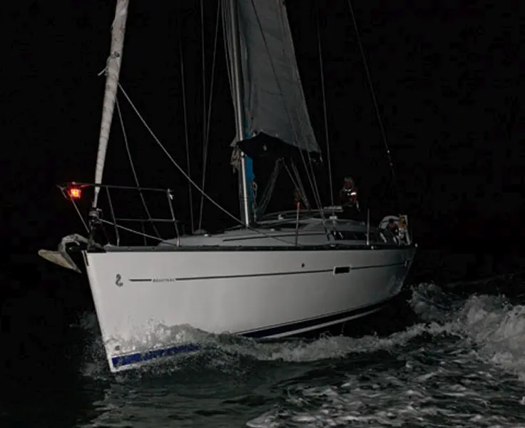 Yacht under sail at dusk during RYA Coastal Skipper night passage