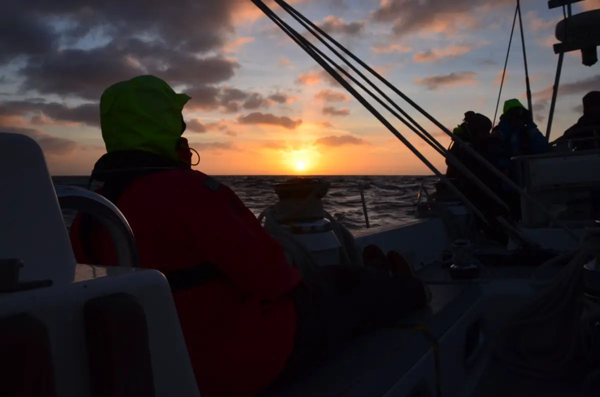 Crew settling in to a night watch sailing along the Dorset Coast as the sun sets