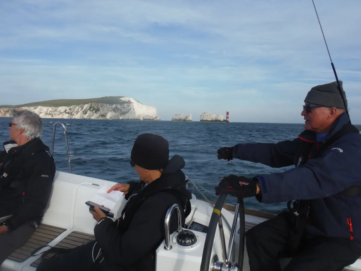 Student skippering yacht along Dorset Coast under instructor supervision