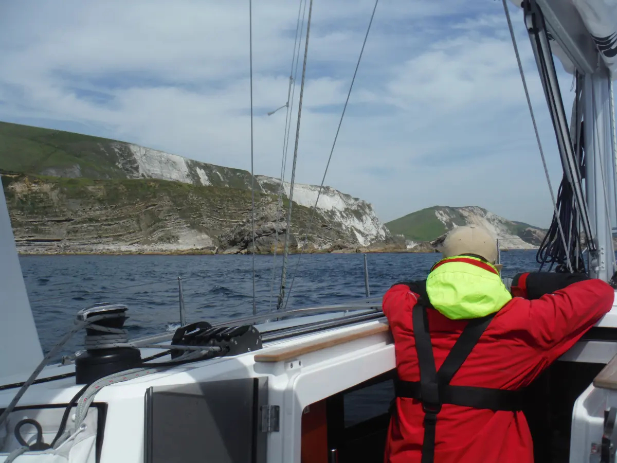 Yacht sailing along the Dorset Jurassic Coast cliffs near Durdle door